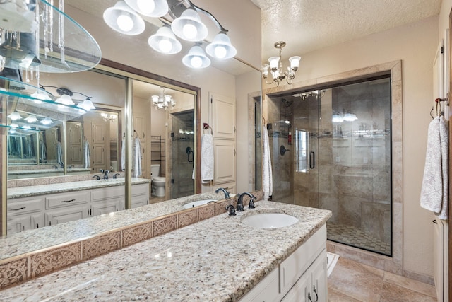 full bathroom featuring toilet, a stall shower, a textured ceiling, vanity, and a chandelier