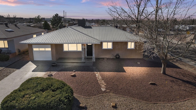 view of front of home featuring metal roof, an attached garage, and stucco siding