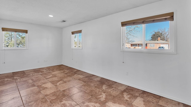 unfurnished room featuring a wealth of natural light, visible vents, and baseboards