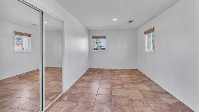 unfurnished room with recessed lighting, plenty of natural light, visible vents, and baseboards