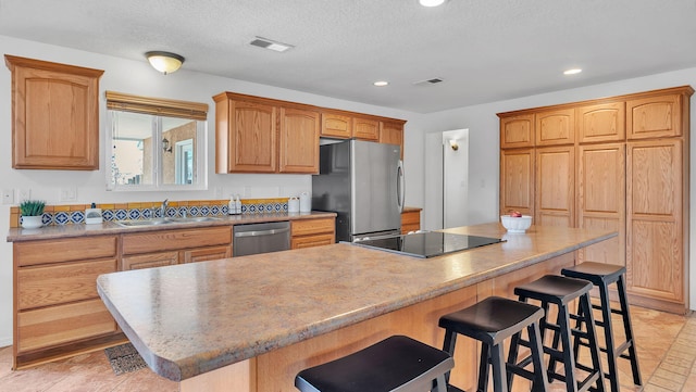 kitchen featuring recessed lighting, stainless steel appliances, a sink, visible vents, and a kitchen breakfast bar