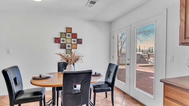 dining area with french doors, visible vents, a textured ceiling, and light tile patterned floors