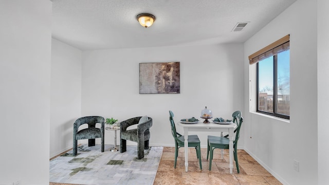 dining room with a textured ceiling, visible vents, and baseboards