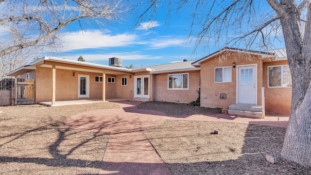 rear view of house featuring metal roof, central air condition unit, french doors, stucco siding, and a patio area