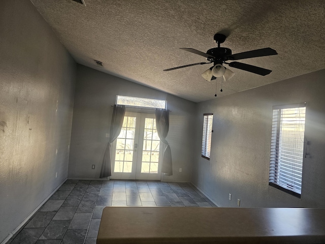 unfurnished room featuring lofted ceiling, french doors, ceiling fan, and a textured ceiling