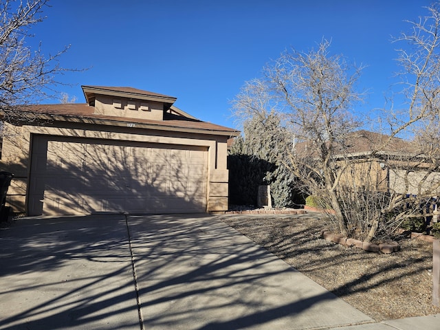 view of side of home featuring a garage, driveway, and stucco siding