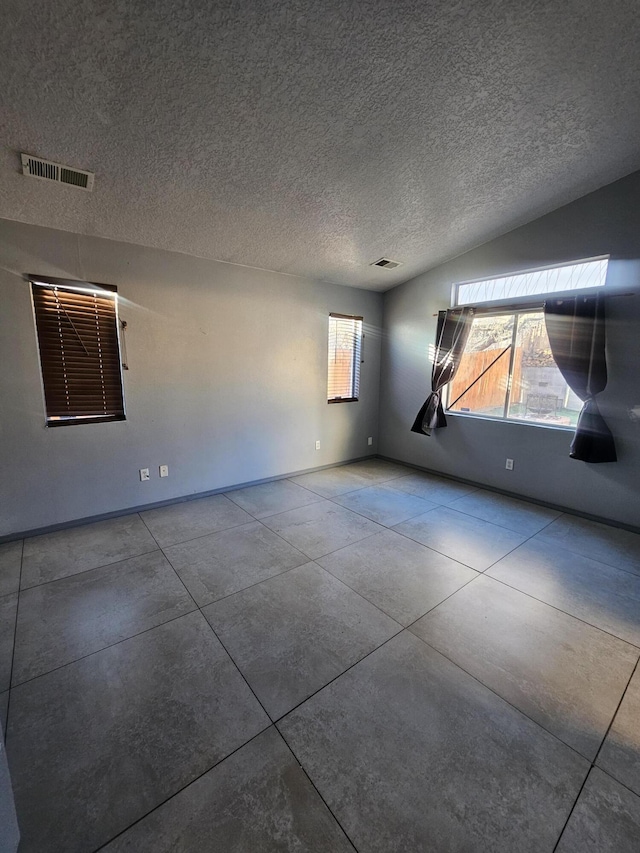 unfurnished room with a textured ceiling, plenty of natural light, and visible vents