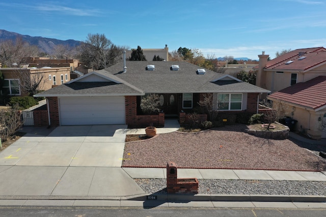 single story home featuring brick siding, a shingled roof, a mountain view, a garage, and driveway