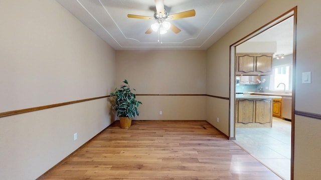 spare room with a ceiling fan, light wood-type flooring, and a sink