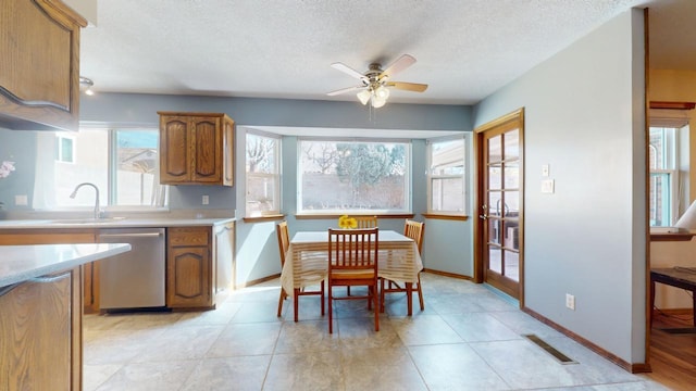 kitchen with baseboards, dishwasher, brown cabinets, light countertops, and a textured ceiling