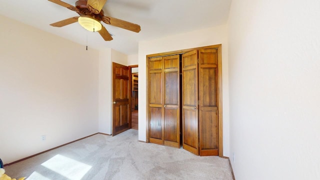 unfurnished bedroom featuring ceiling fan, baseboards, a closet, and light colored carpet