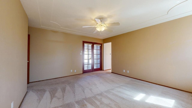 carpeted empty room with a ceiling fan, french doors, and baseboards