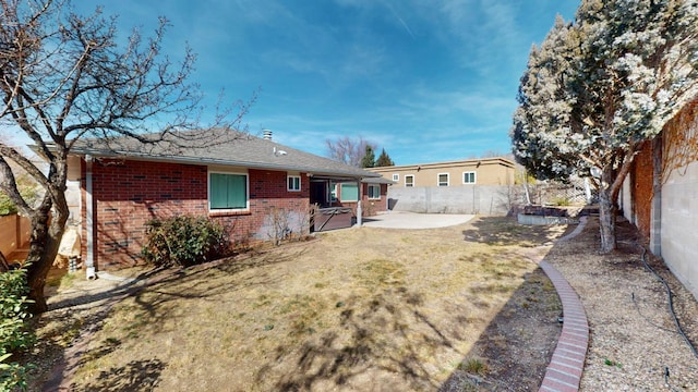 rear view of property with a patio area, brick siding, a lawn, and a fenced backyard