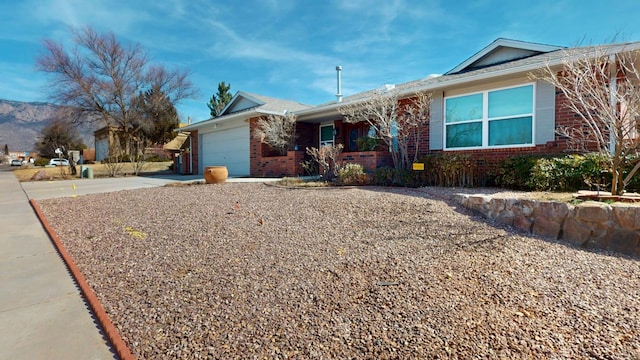 ranch-style home with concrete driveway, brick siding, and an attached garage