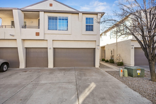 view of front facade with a garage, concrete driveway, a balcony, and stucco siding