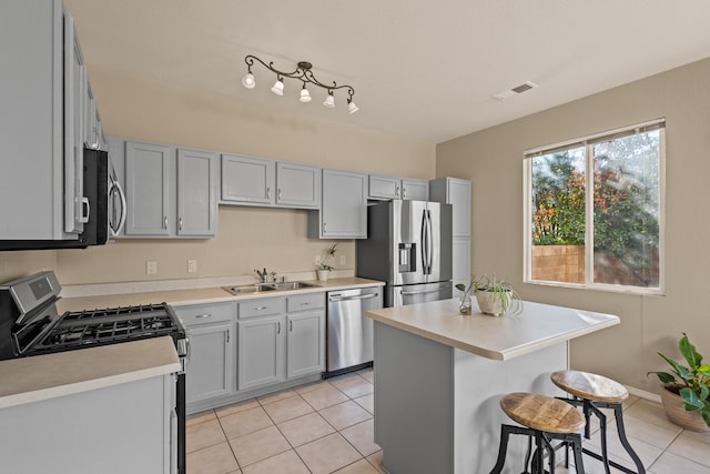 kitchen featuring visible vents, appliances with stainless steel finishes, a breakfast bar, light countertops, and a sink