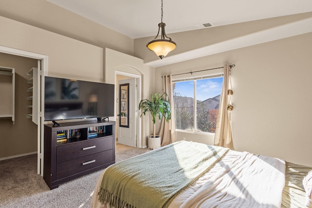 bedroom with a walk in closet, visible vents, and light colored carpet