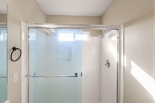 bathroom with a shower stall and a textured wall