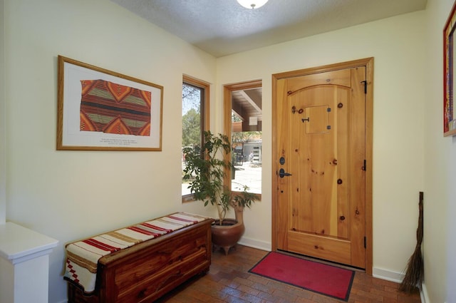 entrance foyer featuring brick floor, plenty of natural light, and baseboards