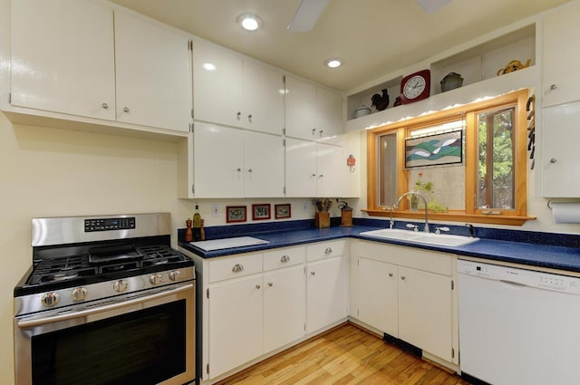 kitchen featuring stainless steel gas stove, dark countertops, white dishwasher, and a sink