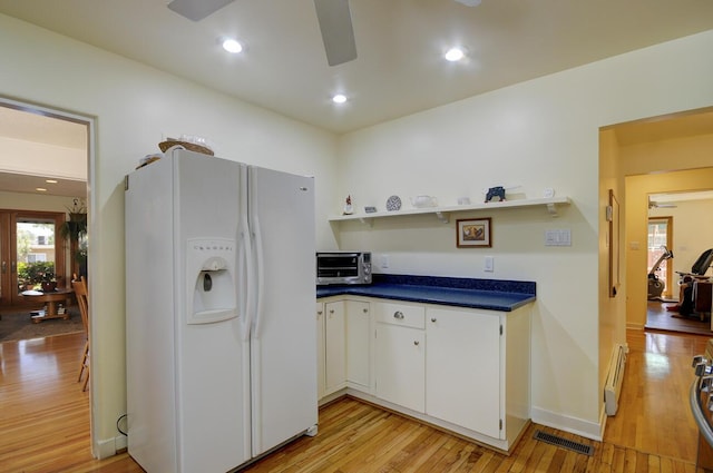 kitchen featuring white fridge with ice dispenser, light wood-style floors, ceiling fan, and dark countertops