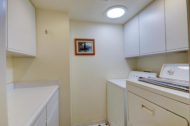 washroom featuring cabinet space, baseboards, and washer and clothes dryer