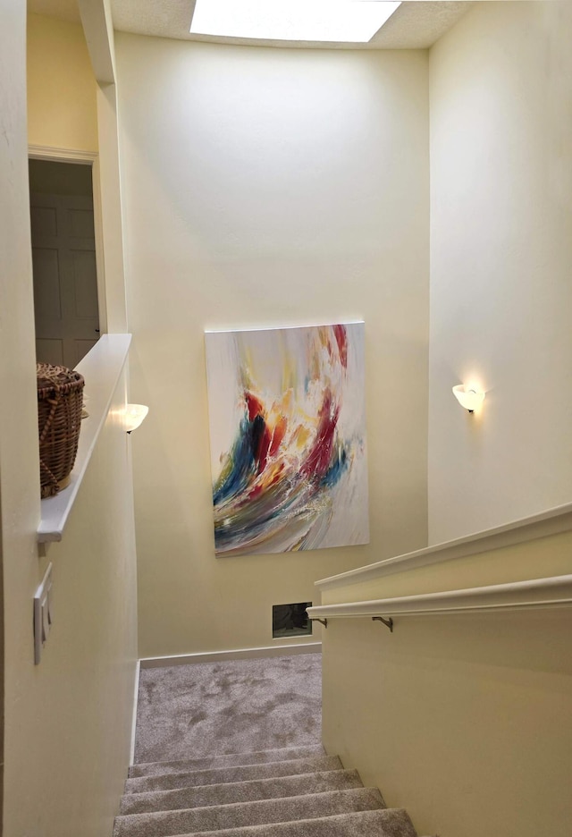 staircase featuring carpet floors, a skylight, and baseboards