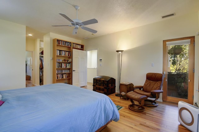 bedroom with access to exterior, visible vents, ceiling fan, a textured ceiling, and wood finished floors