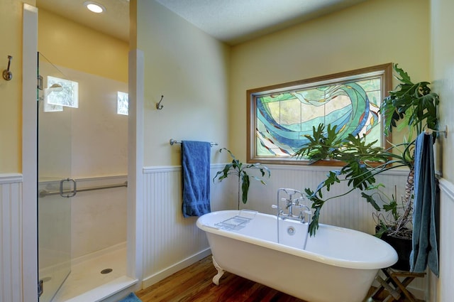 full bathroom featuring a soaking tub, a stall shower, wood finished floors, and wainscoting