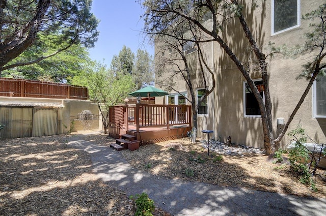 exterior space with a wooden deck, fence, and stucco siding