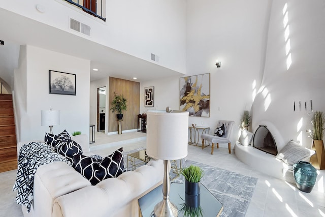 living area with a towering ceiling, stairway, light tile patterned floors, and visible vents