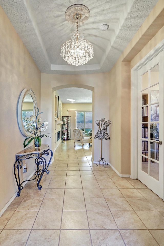 9316 Iron Creek Ln NW, Albuquerque, NM 87120 - hallway featuring arched walkways, light tile patterned flooring, a chandelier, and french doors