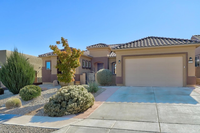 mediterranean / spanish home with driveway, a garage, a tiled roof, a gate, and stucco siding