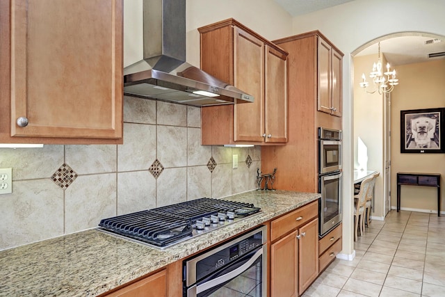 9316 Iron Creek Ln NW, Albuquerque, NM 87120 - kitchen featuring wall chimney range hood, stainless steel appliances, light tile patterned floors, a chandelier, and backsplash