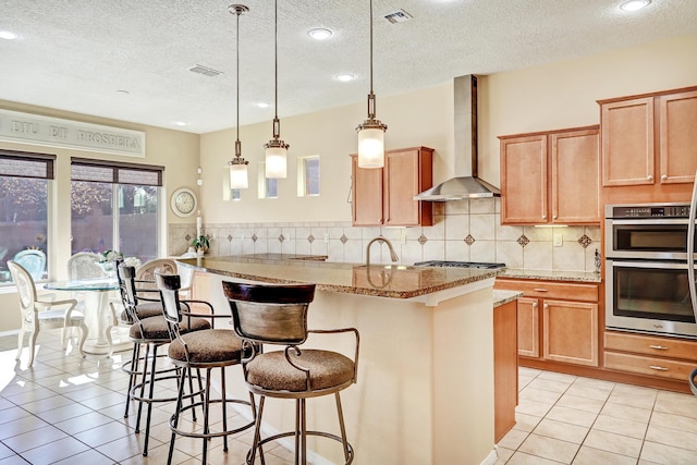 9316 Iron Creek Ln NW, Albuquerque, NM 87120 - kitchen with wall chimney exhaust hood, light tile patterned flooring, a textured ceiling, light stone counters, and a breakfast bar
