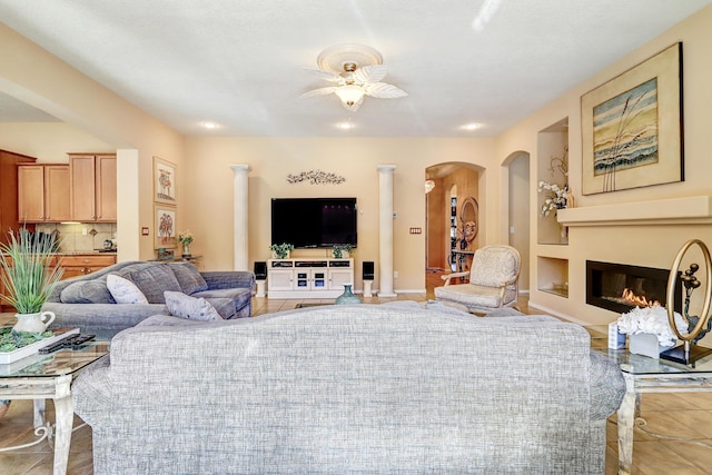 9316 Iron Creek Ln NW, Albuquerque, NM 87120 - living room with light tile patterned floors, a glass covered fireplace, arched walkways, and ceiling fan