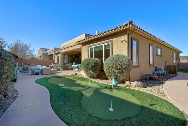 9316 Iron Creek Ln NW, Albuquerque, NM 87120 - back of house featuring an area to practice putting, a patio, an outdoor living space, and stucco siding