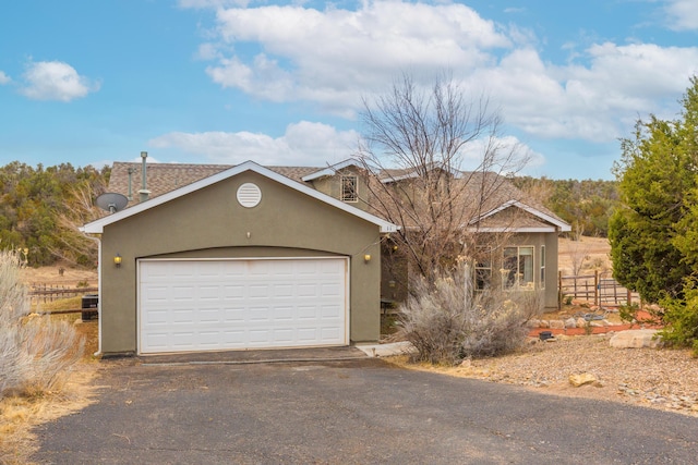 view of front of house with a garage, aphalt driveway, fence, and stucco siding