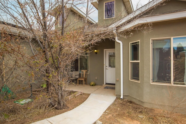 entrance to property with washer / clothes dryer, a patio area, and stucco siding