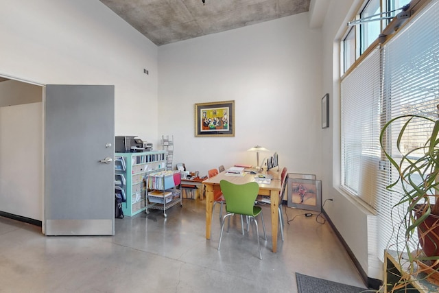 office with baseboards, finished concrete flooring, and a towering ceiling