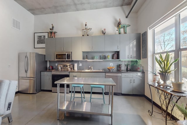 kitchen with visible vents, stainless steel appliances, concrete flooring, and a sink