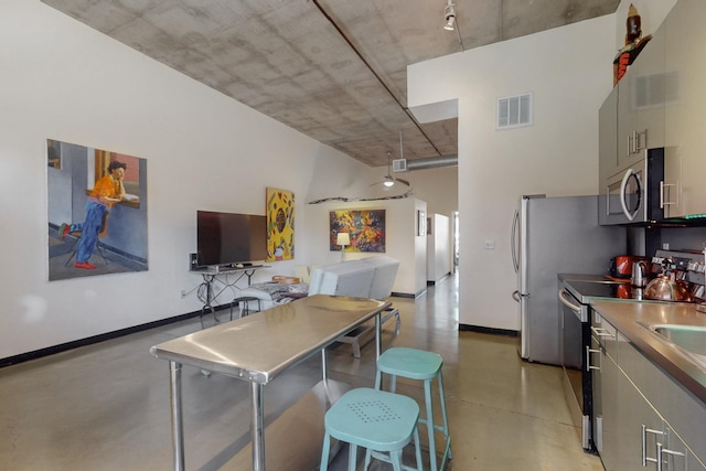 kitchen featuring baseboards, finished concrete flooring, visible vents, and stainless steel appliances