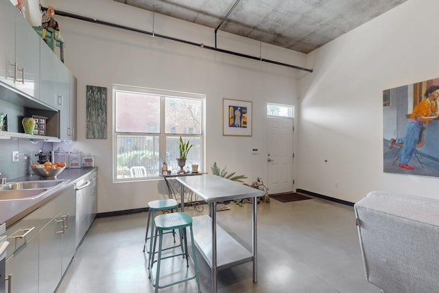 kitchen featuring a sink, finished concrete flooring, baseboards, dishwasher, and open shelves