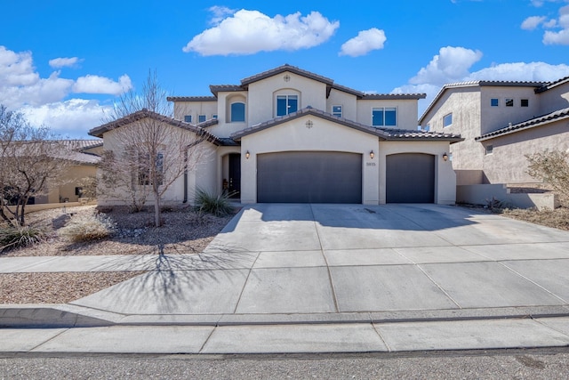 mediterranean / spanish home featuring a garage, a tile roof, concrete driveway, and stucco siding