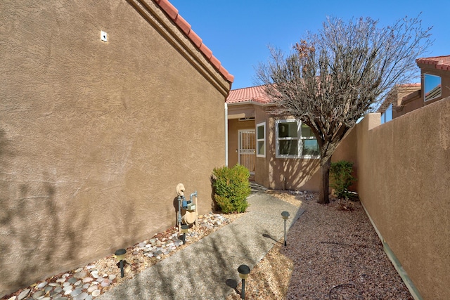 view of home's exterior with stucco siding, fence, and a tiled roof