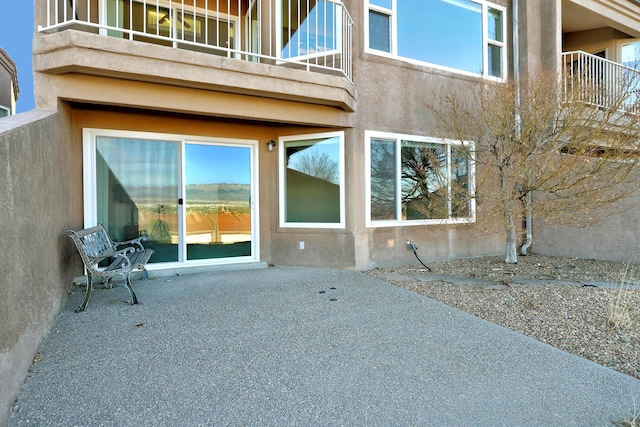 rear view of property featuring a balcony, a patio area, and stucco siding