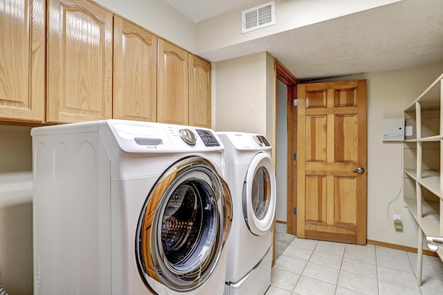 laundry area with light tile patterned floors, visible vents, baseboards, independent washer and dryer, and cabinet space