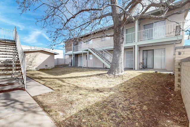 rear view of house with stairway and stucco siding