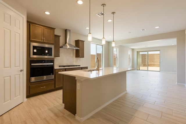 2178 Janet Way, Rio Rancho, NM 87144 - kitchen with stainless steel appliances, wall chimney exhaust hood, a sink, a kitchen island with sink, and plenty of natural light