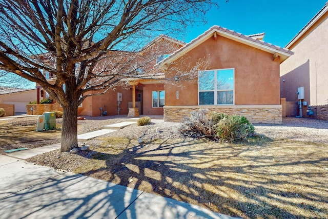 view of front of house with stone siding, a tiled roof, and stucco siding